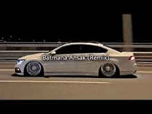a white car is driving down a highway at night with a bridge in the background .