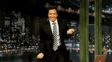 a man in a suit and tie is dancing in front of a window .