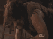 a man with curly hair and a beard is laying on the floor with a cw logo on the bottom right
