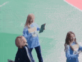 a group of girls are standing on a green field . one of the girls is holding a book .
