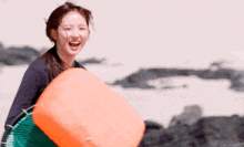 a woman is laughing while holding an orange object