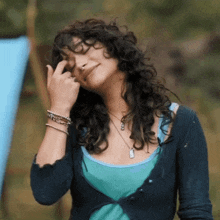 a woman with curly hair is wearing a blue sweater and a blue tank top