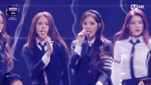 a group of girls are on a stage with a mnet logo in the background