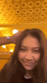 a girl with long hair is smiling in front of a ceiling with circles .