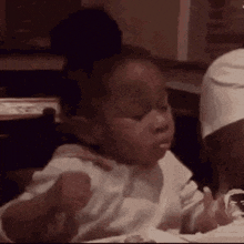 a baby is sitting at a table eating a sandwich .