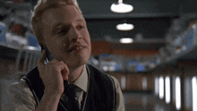 a man in a vest is talking on a cellphone