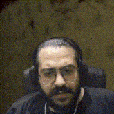 a bearded man wearing headphones and glasses is making a funny face