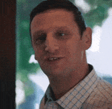 a man wearing a plaid shirt is smiling for the camera