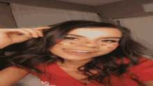 a woman in a red shirt with hearts on her face smiles