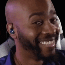 a bald man with a beard is smiling while wearing headphones .