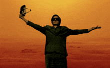 a man with his arms outstretched holds a pair of sunglasses