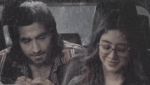 a man and a woman are sitting in a car in the rain looking at their phones .