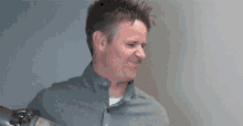a man in a grey shirt is holding a metal object in his hand