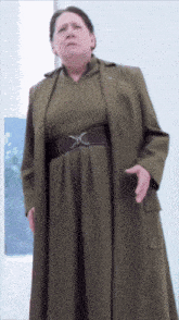 a woman in a green dress with a belt that has a x on it