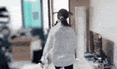 a woman in a white shirt is walking through a room