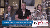a group of people sitting at a table with microphones in front of a sign that says ' tv '