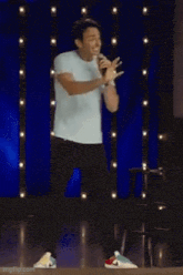 a man is standing on a stage with a microphone and the words technically speaking behind him