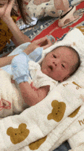a baby is laying on a pillow with a teddy bear pattern