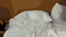 a bed with white sheets and pillows and a clock on the nightstand