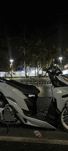 a white honda scooter is parked on the side of the road at night