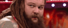 a man with dreadlocks and a beard is standing in a wrestling ring .