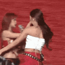 two women are standing next to each other on a stage and hugging each other .