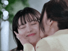 a woman kissing another woman 's cheek with her eyes closed