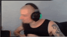 a man with a tattoo on his arm is wearing headphones while sitting in front of a computer screen .