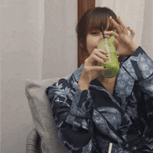 a woman sitting in a chair drinking a green drink