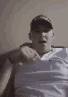 a man wearing a baseball cap and a white shirt is laying on a couch .
