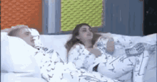 a man and a woman are laying on a bed covered in white sheets .