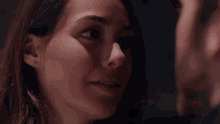 a close up of a woman 's face with a man 's face in the background