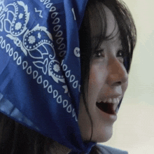a woman wearing a blue bandana with the number 1 on it smiles