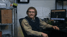 a man sits at a desk in front of a sign that reads signs