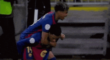 two soccer players are hugging each other on the field while celebrating a goal .