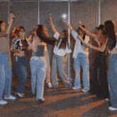 a group of women are dancing in a room with their arms in the air