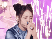 a woman with two buns on her hair is wearing a headset and holding a blue object in her hand .