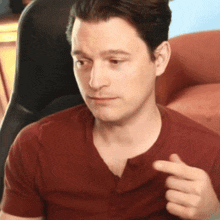 a man in a red shirt is pointing his finger at something
