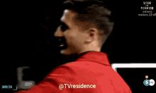 a man in a red jacket kisses a woman in a black dress on tv residence