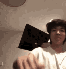 a young man is holding a laptop in his hand and making a face .