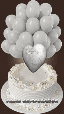 a birthday cake with a heart and balloons and the words feliz cumpleanos on the bottom