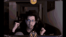 a man wearing glasses and headphones is sitting in front of a screen with a gold coin on it