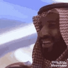 a man with a beard is wearing a sheikh 's head scarf and smiling .