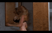 a woman in a black bra is dancing in front of a wooden door