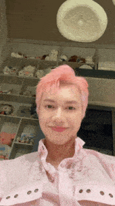 a man with pink hair is smiling in front of a shelf of stuffed animals