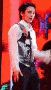a man in a vest and tie is standing on a stage .