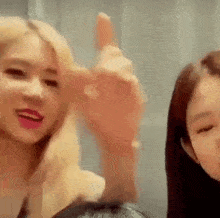 a couple of girls are standing next to each other and one of them is giving a thumbs up sign .