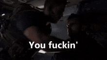 a man is standing next to another man in a dark room .
