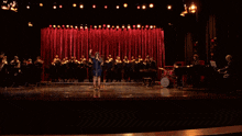 a woman singing into a microphone in front of a choir with a drum that says jazz