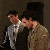 two men standing next to each other with one wearing a jacket with a flag on it
